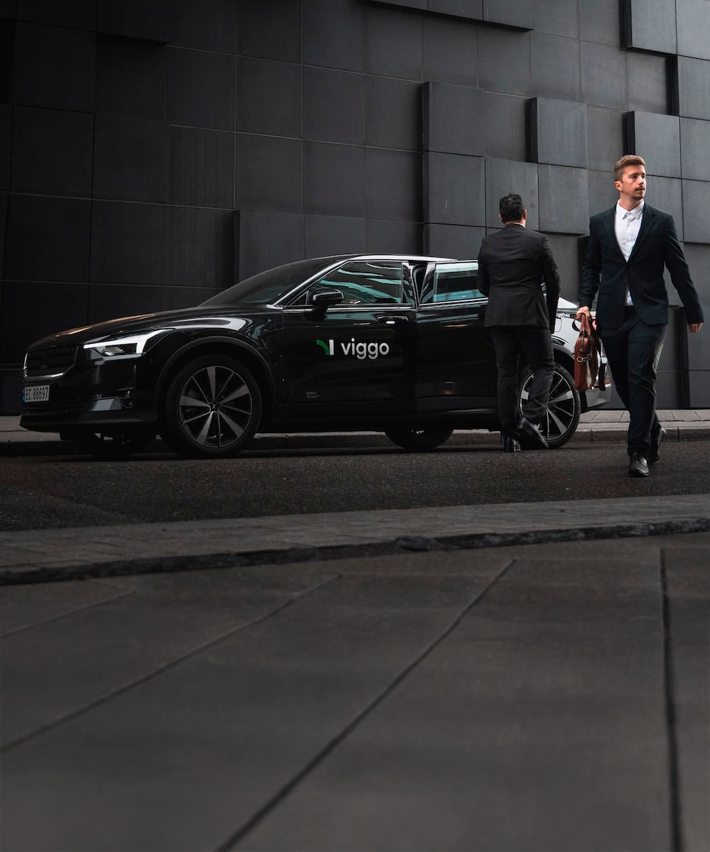 A Viggo car parked on a dark street as a driver walks up to it.